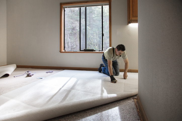 mężczyzna instaluje wykładzinę dywanową